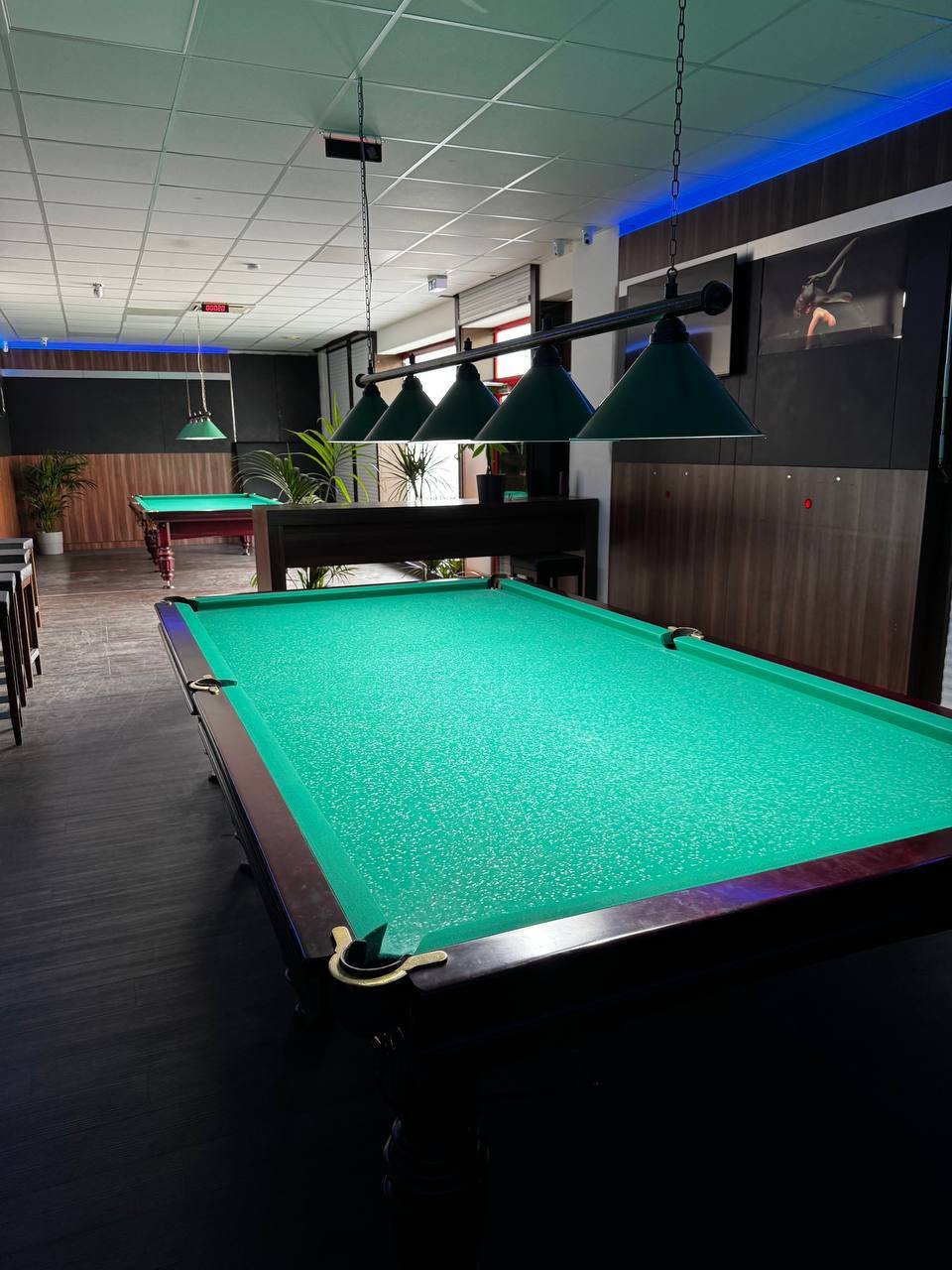 Бильярдные столы с зелёным сукном и подвесными светильниками в клубе Billard O., Оберхаузен