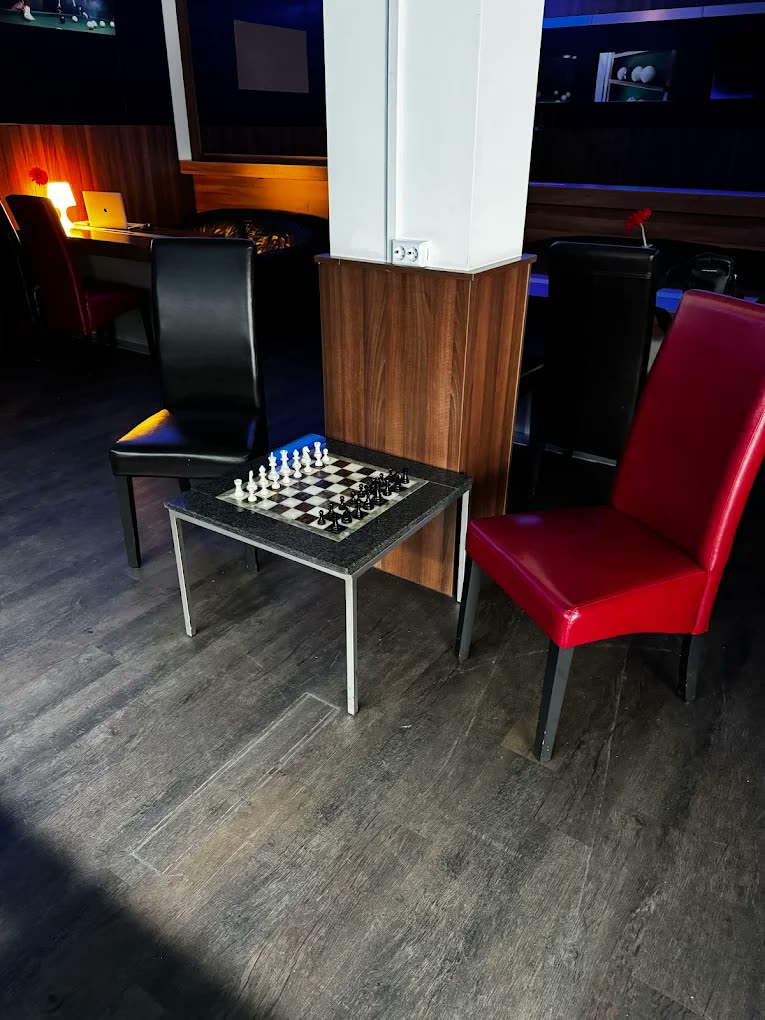 Шахматный столик между красным и черным креслом в зоне отдыха Billard O.